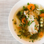 Provencial Fish Soup in a white bowl on top of a burlap tablecloth